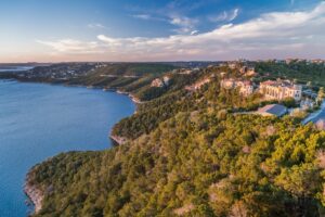 View of Lake Travis Austin Texas from above with green cliffs on the right and blue water on the left