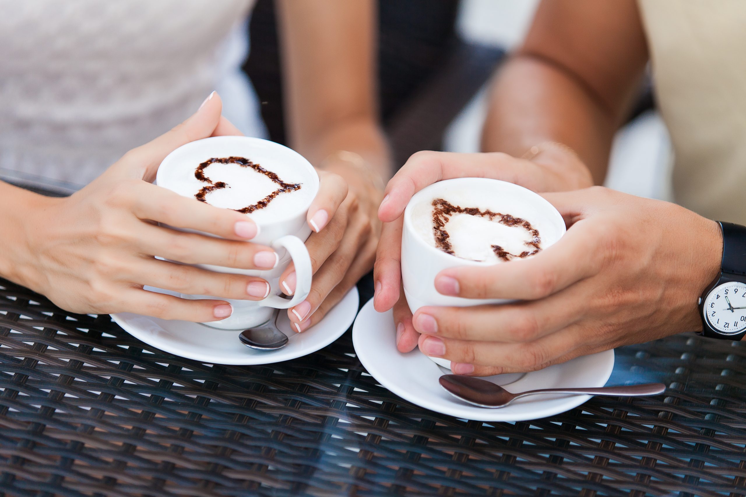 couple holding lattes with hearts on them--some of the best dallas date ideas and romantic things to do in dallas for couples include stopping for coffee