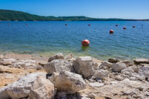 rocky beach on lake travis with swimming bouys on the water, best austin beaches guide