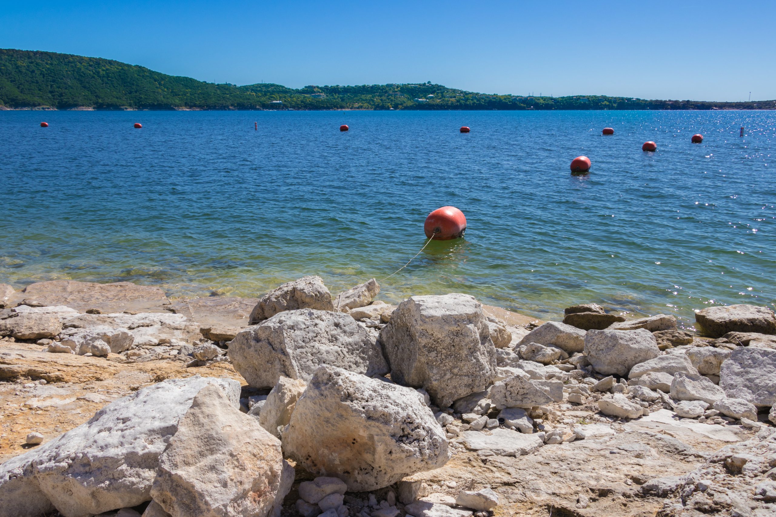 rocky beach on lake travis with swimming bouys on the water, best austin beaches guide