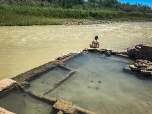 woman sitting on the edge of langford springs, one of the best hot springs in texas